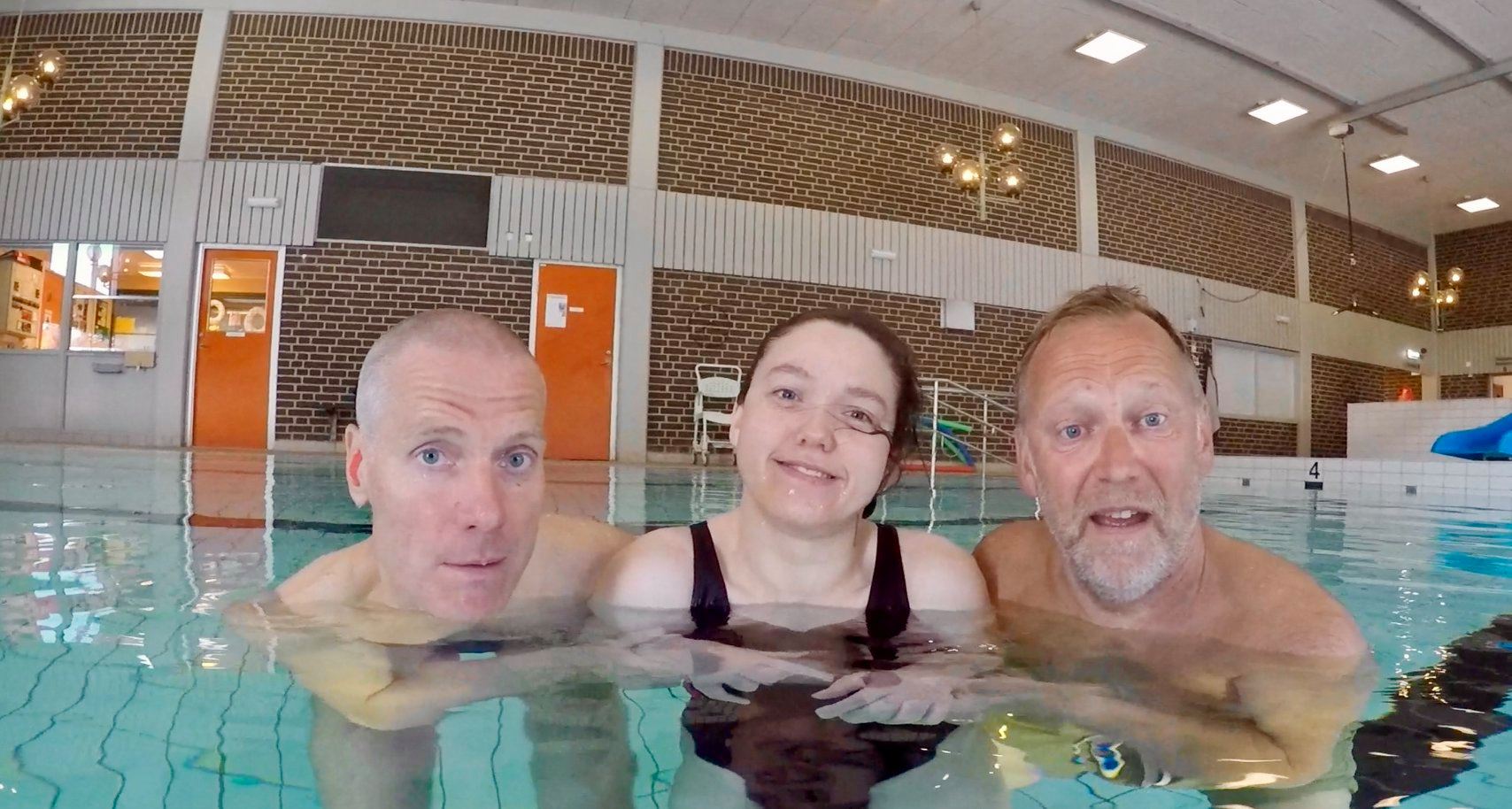 Tre personer i en simbassäng