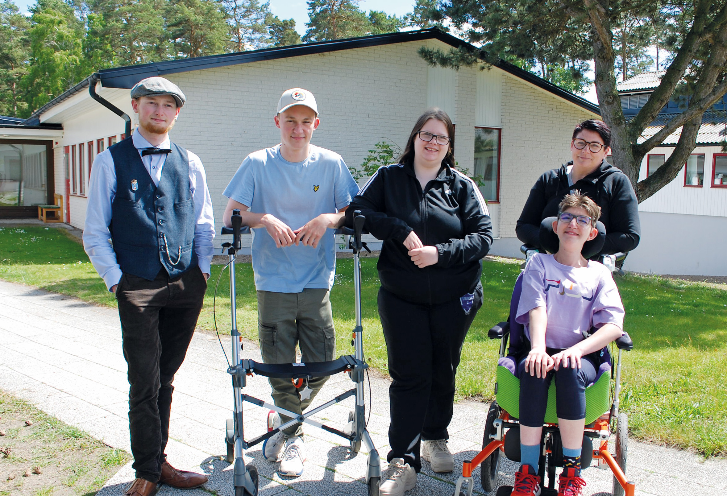 Fem glada personer poserar framför aulan i Furuboda-Yngsjö en solig sommardag.