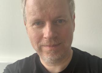 En kortklippt man med svart t-shirt