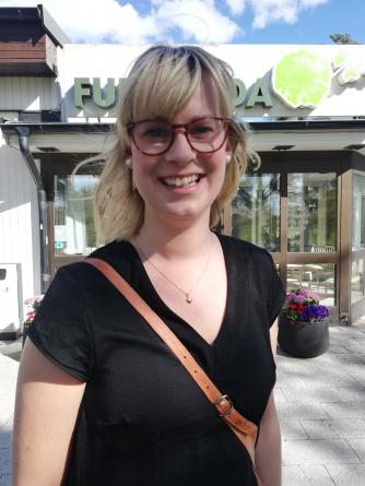 Leende kvinna i svart t-shirt och markerade glasögon