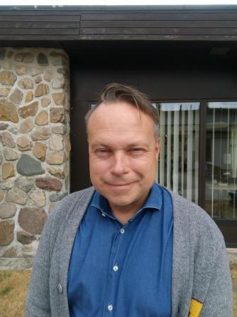 Man med blå skjorta och grå kofta