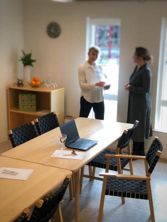 Ett konferensbord och i bakgrunden samspråkar två personer