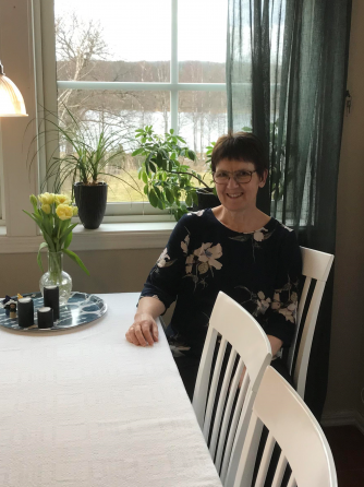 Kortklippt leende kvinna sittande vid ett köksbord