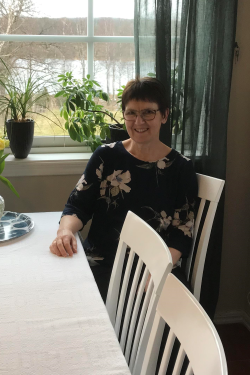 Kortklippt leende kvinna sittande vid ett köksbord