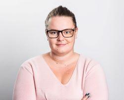 Kvinna i glasögon, rosa tröja och målade naglar i mörk färg