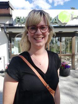 Leende kvinna i svart t-shirt och markerade glasögon